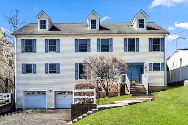 view of front of home featuring driveway, a front lawn, fence, an attached garage, and a shingled roof