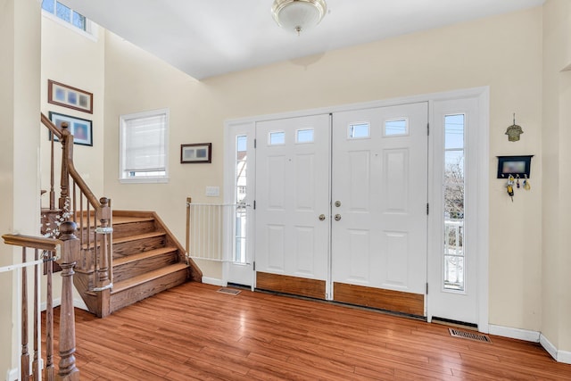 entrance foyer featuring visible vents, stairway, baseboards, and hardwood / wood-style floors