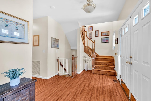foyer entrance featuring light wood-type flooring, visible vents, baseboards, and stairs