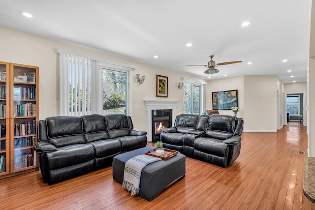 living area with light wood finished floors, visible vents, ceiling fan, recessed lighting, and a glass covered fireplace