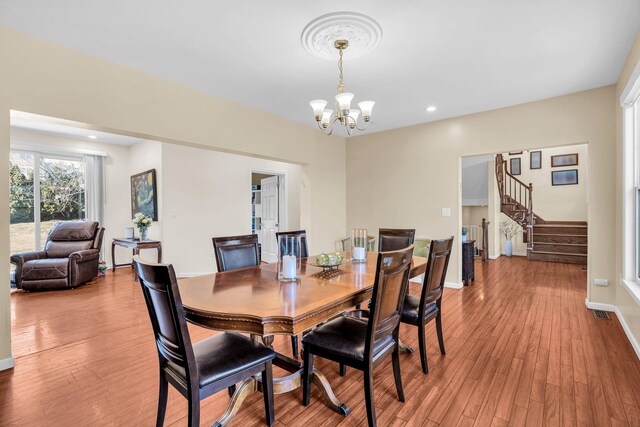 dining area featuring light wood finished floors, baseboards, stairs, and an inviting chandelier