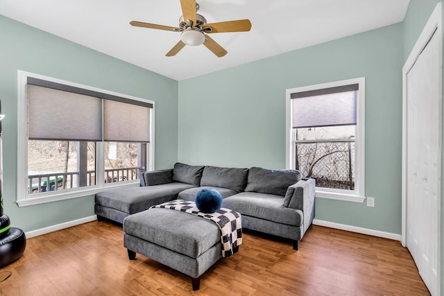 living area with baseboards, wood finished floors, and a ceiling fan