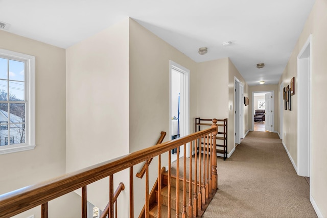 hall featuring visible vents, an upstairs landing, baseboards, and light carpet