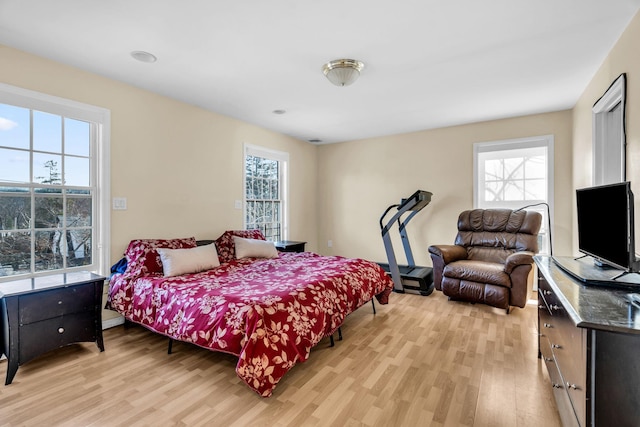 bedroom with light wood finished floors and multiple windows