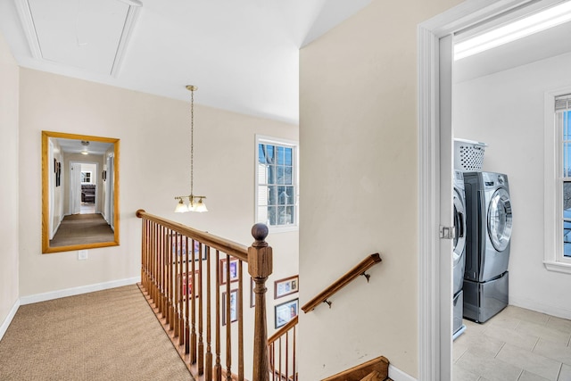 hallway featuring an upstairs landing, attic access, baseboards, and washing machine and clothes dryer