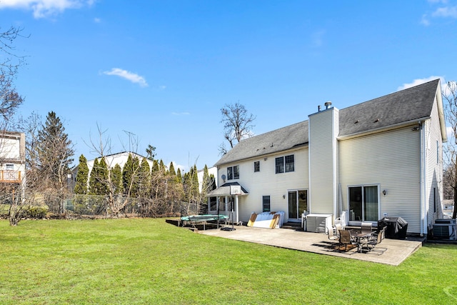 back of property with a patio area, a lawn, a chimney, and central AC