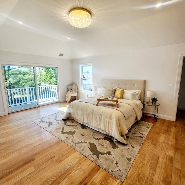 bedroom featuring access to exterior, vaulted ceiling, wood finished floors, baseboards, and a chandelier