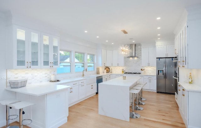 2566 Aster Pl N, Westbury, NY 11590 - kitchen with stainless steel appliances, wall chimney range hood, a breakfast bar, white cabinets, and decorative backsplash