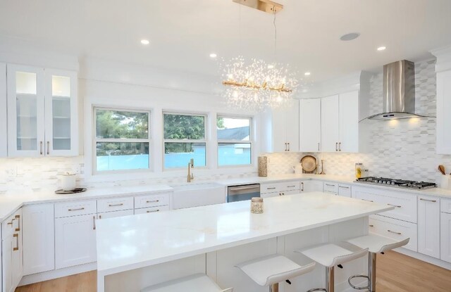 2566 Aster Pl N, Westbury, NY 11590 - kitchen featuring wall chimney range hood, appliances with stainless steel finishes, a breakfast bar, backsplash, and recessed lighting