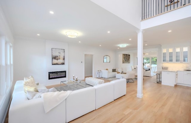 2566 Aster Pl N, Westbury, NY 11590 - living room featuring decorative columns, a glass covered fireplace, recessed lighting, and light wood-type flooring