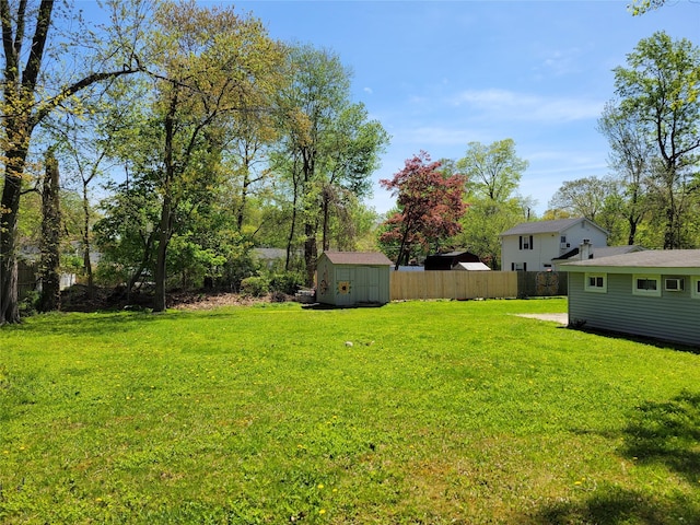 view of yard featuring a storage shed, fence, and an outbuilding