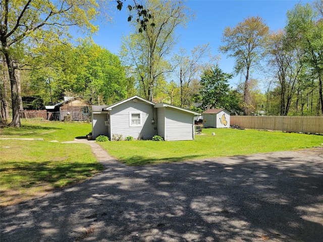 view of home's exterior with a storage shed, fence, an outdoor structure, and a yard