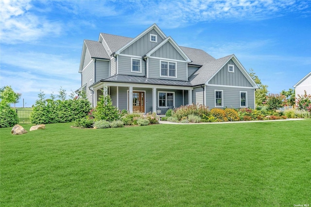 craftsman-style house with a standing seam roof, covered porch, board and batten siding, and a front lawn