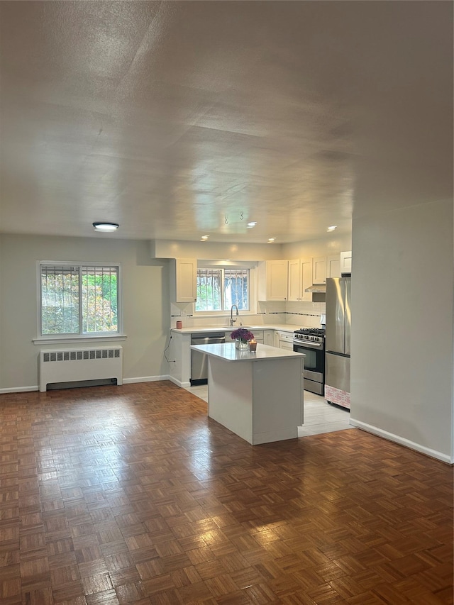 3317 Hone Ave, Bronx, NY 10469 - kitchen featuring radiator heating unit, stainless steel appliances, white cabinetry, a center island, and light countertops
