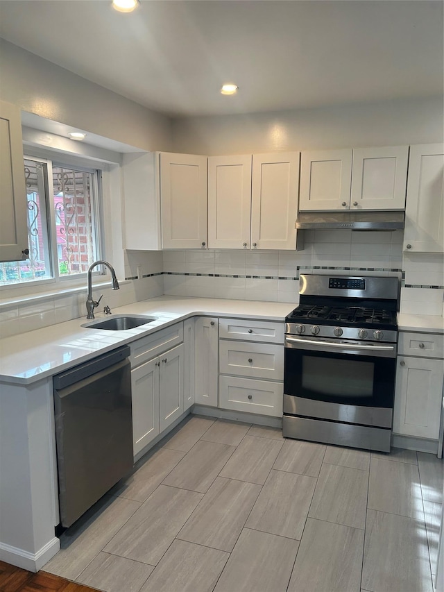 3317 Hone Ave, Bronx, NY 10469 - kitchen with stainless steel appliances, light countertops, under cabinet range hood, decorative backsplash, and wood tiled floors
