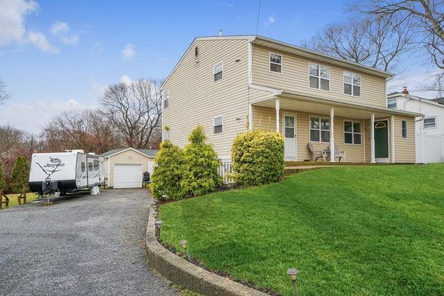 view of front of property with a porch, a detached garage, a front lawn, an outdoor structure, and aphalt driveway