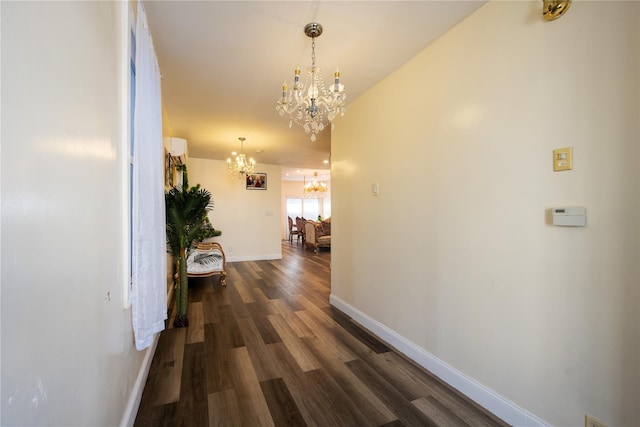 hallway with dark wood-style floors, baseboards, and a chandelier