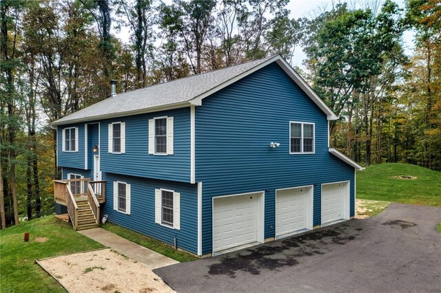 view of home's exterior with aphalt driveway, stairs, a lawn, a deck, and an attached garage