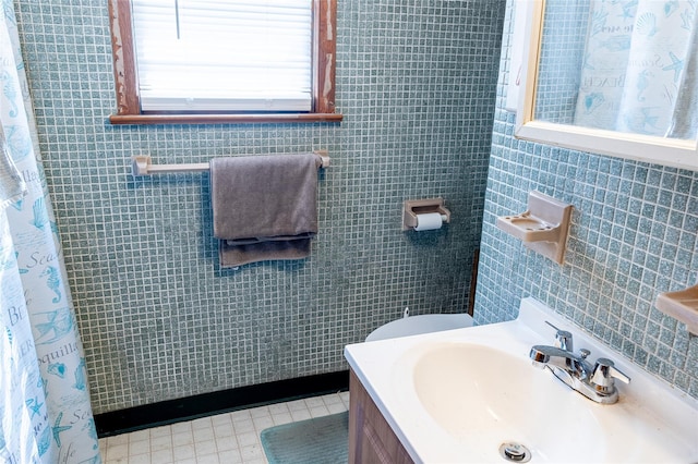 full bath featuring tile patterned floors, tile walls, curtained shower, and vanity