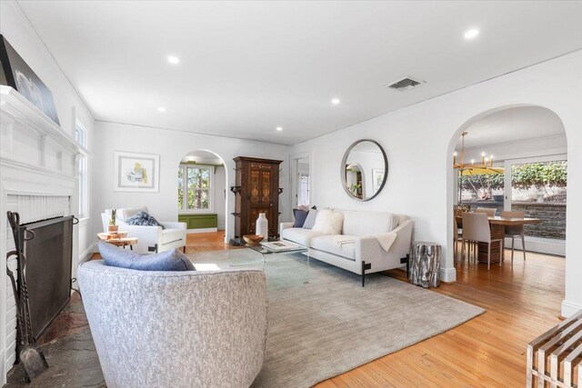 living room featuring wood finished floors, visible vents, arched walkways, recessed lighting, and an inviting chandelier