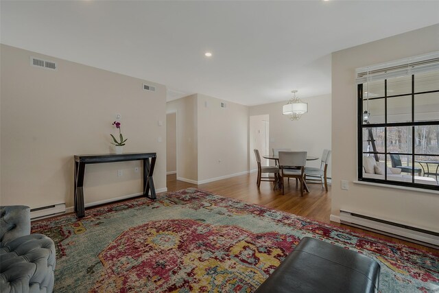 living area with visible vents, wood finished floors, and a baseboard radiator