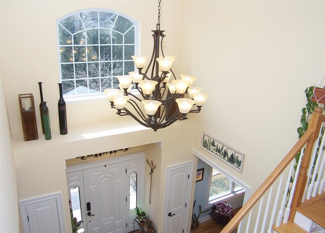 entryway with a notable chandelier, stairway, and a towering ceiling