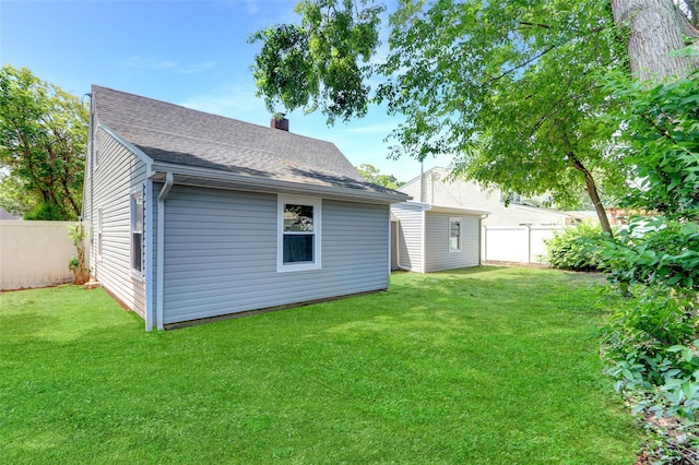 17 Windmill Ln, Levittown, NY 11756 - back of property with an outdoor structure, a chimney, fence, and a lawn