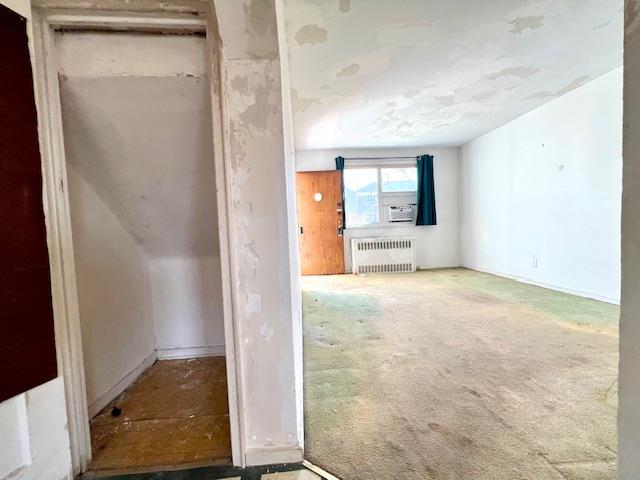 carpeted empty room with cooling unit and radiator