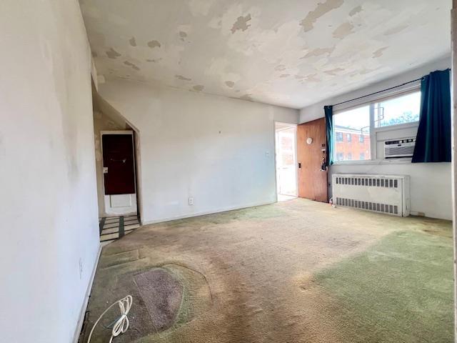 carpeted empty room featuring radiator heating unit