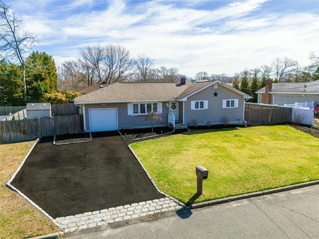 ranch-style house featuring a front yard, fence, a garage, and aphalt driveway