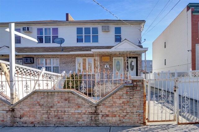 multi unit property with a fenced front yard, a porch, and brick siding