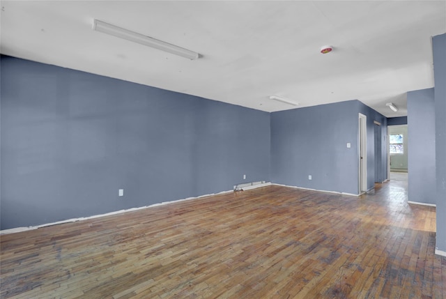 spare room with baseboards and hardwood / wood-style flooring