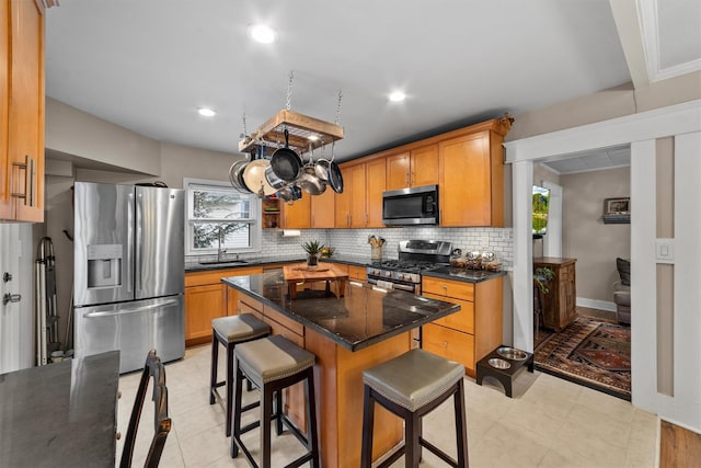 kitchen with a center island, decorative backsplash, a kitchen breakfast bar, stainless steel appliances, and a sink