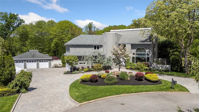 10 Crick Holly Ln, East Islip, NY 11730 - art deco inspired home with driveway, an outbuilding, a shingled roof, and a front lawn