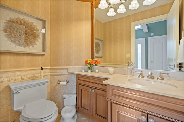 10 Crick Holly Ln, East Islip, NY 11730 - bathroom featuring toilet, vanity, a chandelier, a wainscoted wall, and tile walls