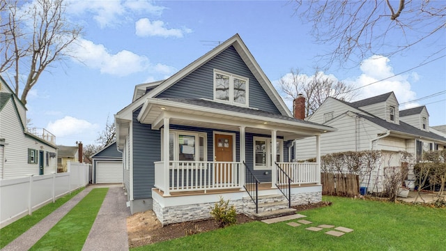 bungalow-style house featuring an outbuilding, a porch, a front lawn, and fence