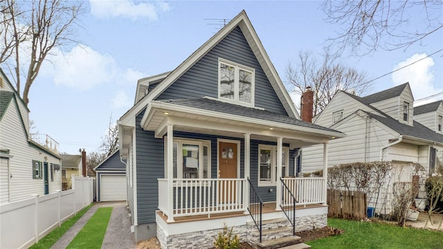 bungalow-style home featuring a porch, a front lawn, roof with shingles, and fence