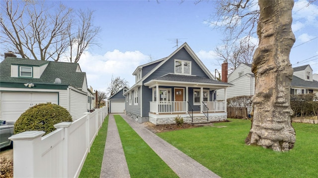 view of front facade featuring fence, a porch, a front lawn, an outdoor structure, and a detached garage