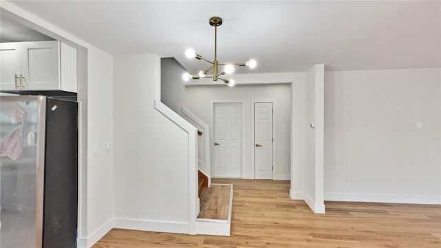entryway with light wood-type flooring, baseboards, a notable chandelier, and stairway