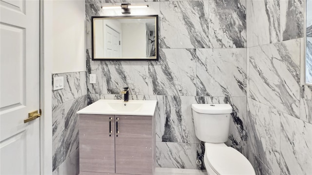 half bathroom featuring toilet, tile walls, and vanity