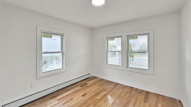 empty room featuring baseboards, baseboard heating, and light wood-type flooring