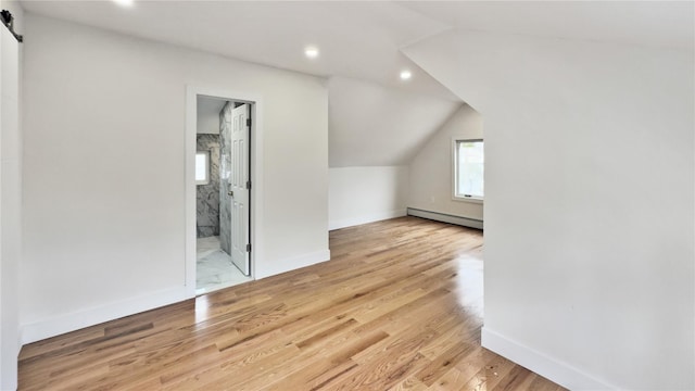 additional living space with a barn door, light wood-style floors, lofted ceiling, and a baseboard radiator