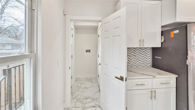 kitchen with decorative backsplash, marble finish floor, white cabinets, and freestanding refrigerator