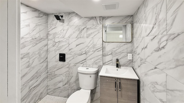 bathroom featuring visible vents, toilet, vanity, and a tile shower