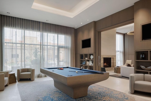 recreation room with a tray ceiling, pool table, recessed lighting, and a premium fireplace