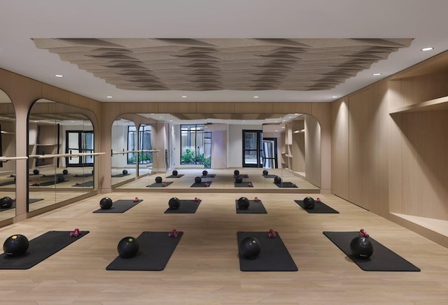 exercise room featuring wood finished floors, arched walkways, and recessed lighting