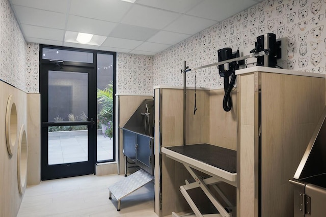 miscellaneous room with a drop ceiling and wallpapered walls