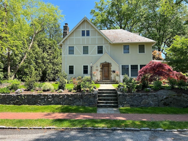 tudor-style house featuring stucco siding and a chimney