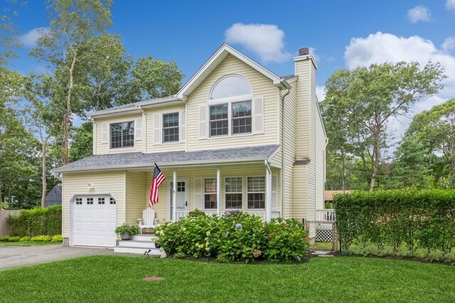 traditional home with aphalt driveway, a garage, a chimney, and a front lawn