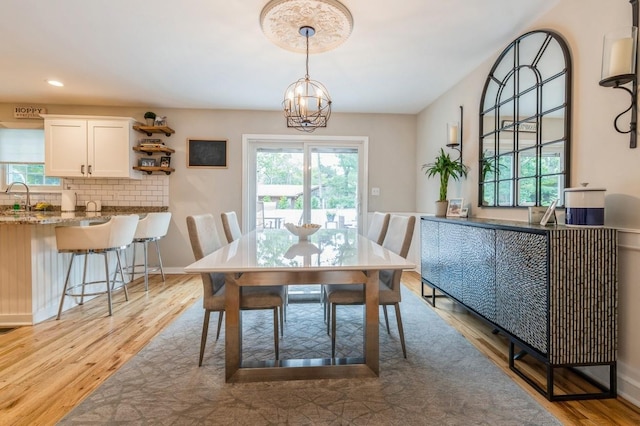 dining area with light wood finished floors, a notable chandelier, recessed lighting, and baseboards
